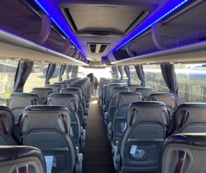 Interiör av buss med bekväma säten och modern belysning för gruppresor och evenemang.